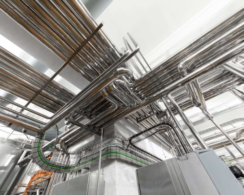 Steel pipelines and cables in factory interior as nuclear industry background concept Modern industry equipment, cables and piping inside in manufacture background